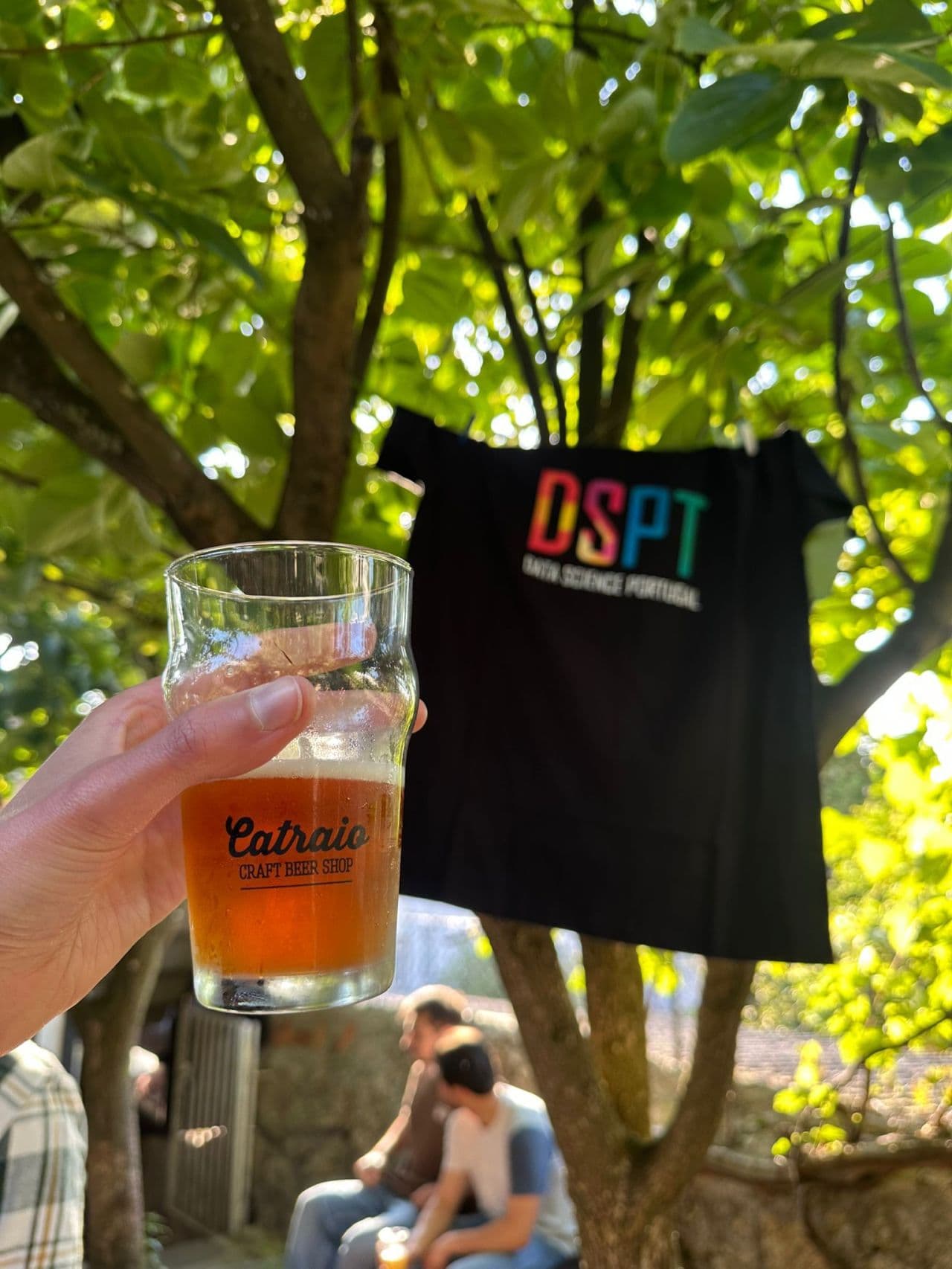 A craft beer raised next to a DSPT t-shirt at a community gathering