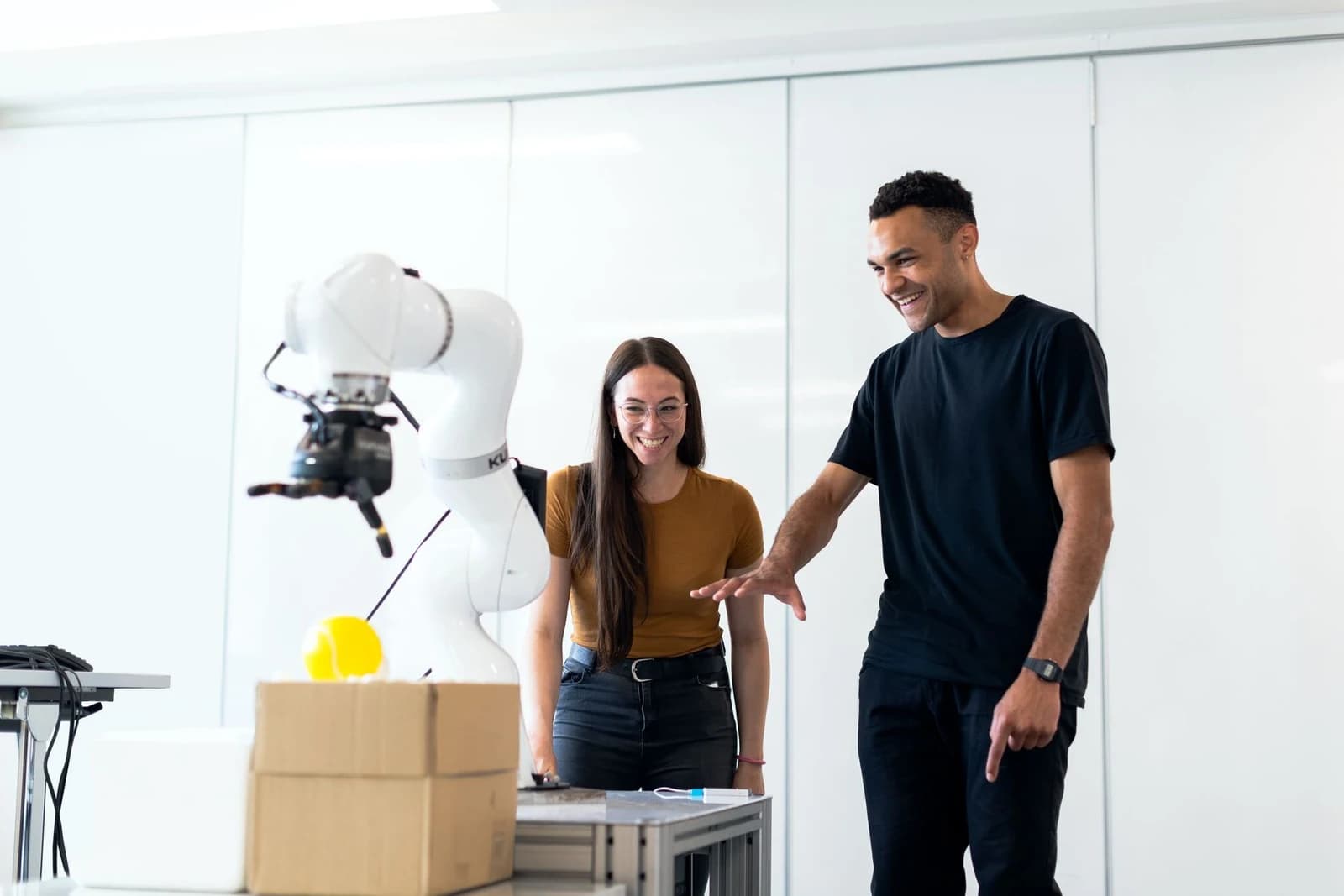 Two engineers developing a robotic arm at a workbench