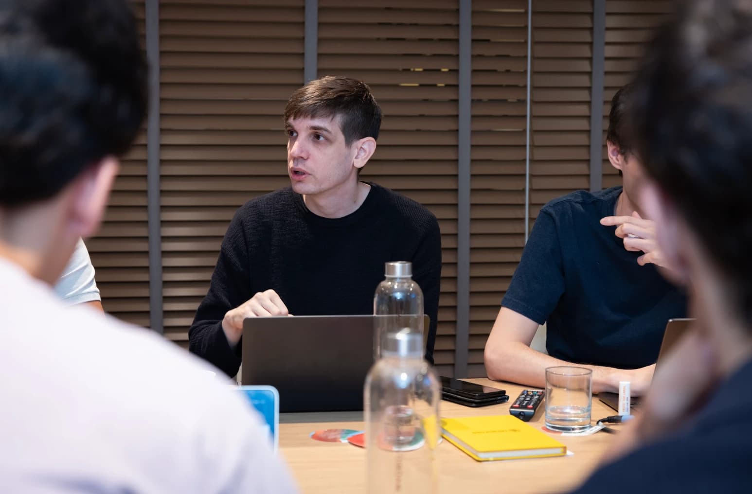 TensorOps colleagues discussing work around a meeting table with laptops and notebooks