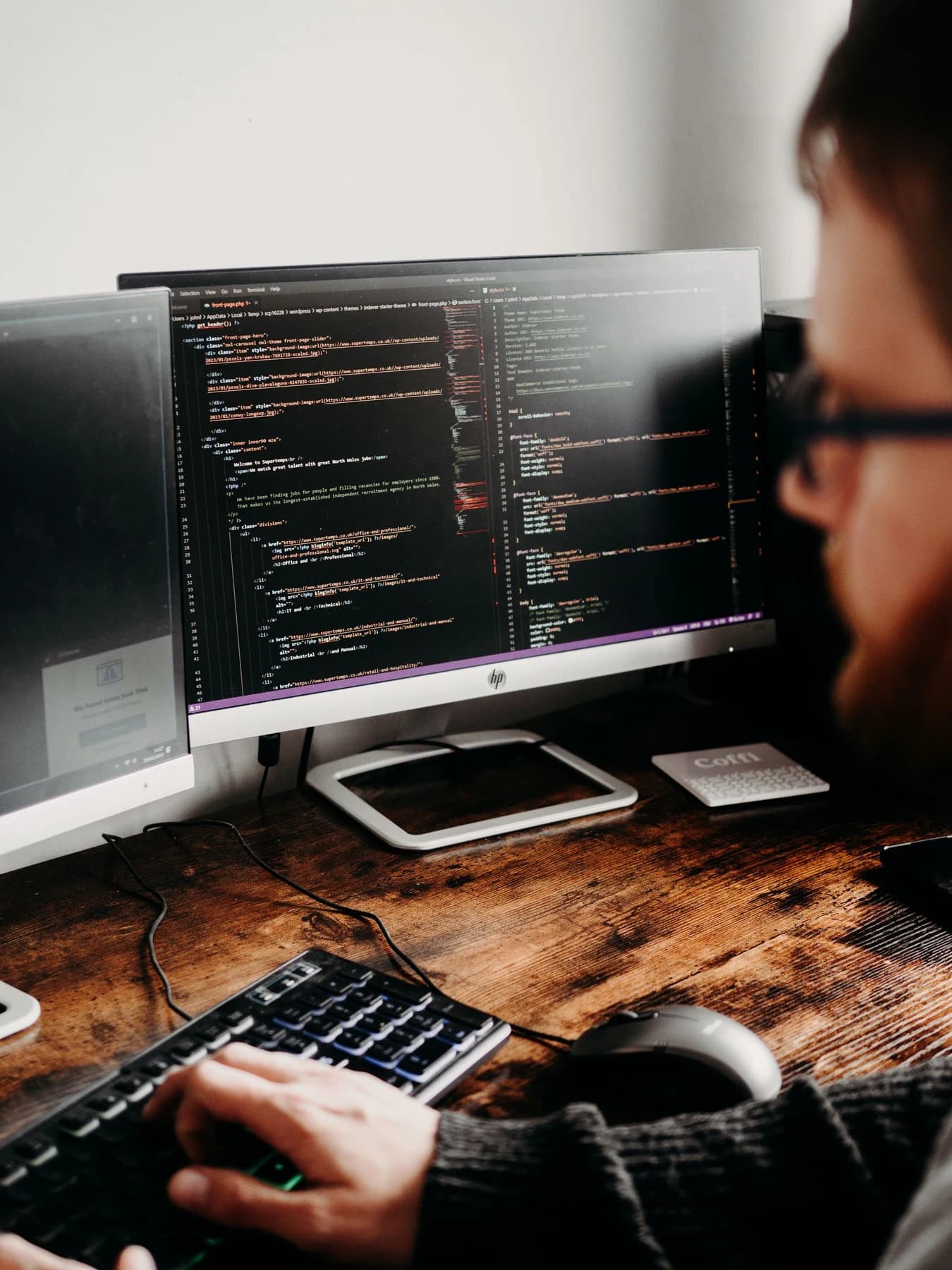 An engineer working with code on two monitors